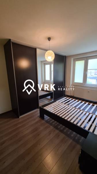 Schlafzimmer in einer 2-Zimmer-Wohnung mit dunklem Kleiderschrank, Bett und Fenster.