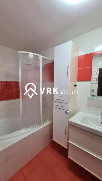 Badezimmer in einer 2-Zimmer-Wohnung mit Duschkabine und Waschbecken, rote Akzente.