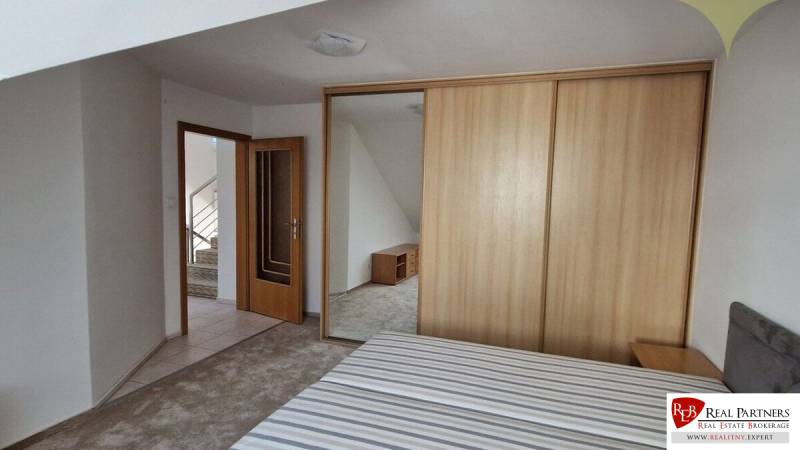 Schlafzimmer im Einfamilienhaus mit einem Holzschrank und offenen Türen zum Flur.