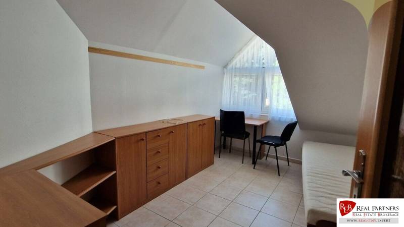 Ein Zimmer in einem Einfamilienhaus mit Stauraum, zwei Stühlen und einem Fenster mit Vorhängen.