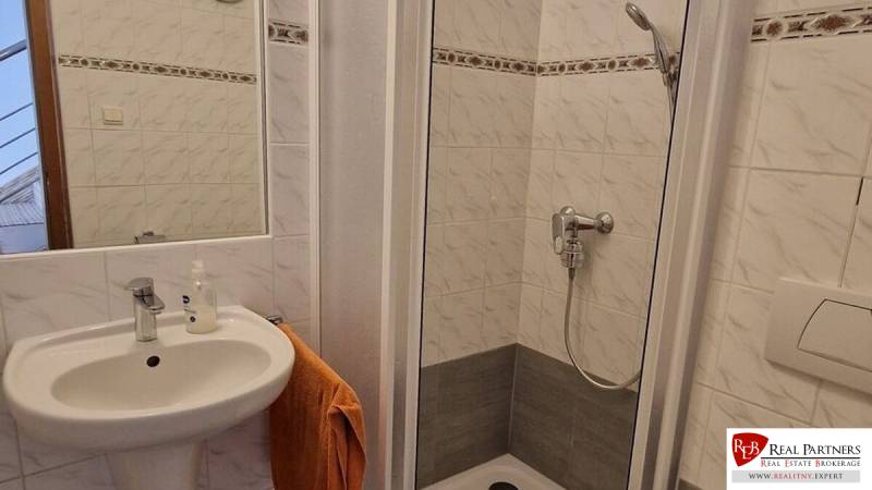 Ein Badezimmer in einem Einfamilienhaus mit Waschbecken und Duschkabine.
