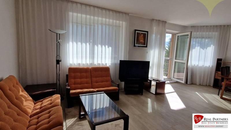 Wohnzimmer mit orangenen Möbeln, Fernseher und großen Fenstern, Einfamilienhaus.