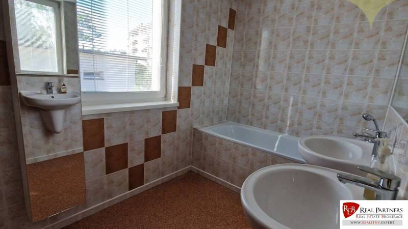 Badezimmer mit Badewanne und Waschbecken in einem Einfamilienhaus, mit Fliesen und Fenster.