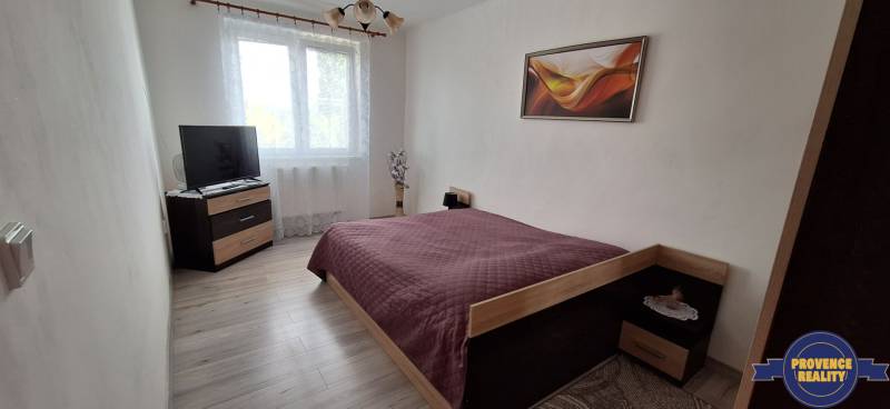 Schlafzimmer in einer 3-Zimmer-Wohnung mit Bett, Fernseher und Wanddekoration.