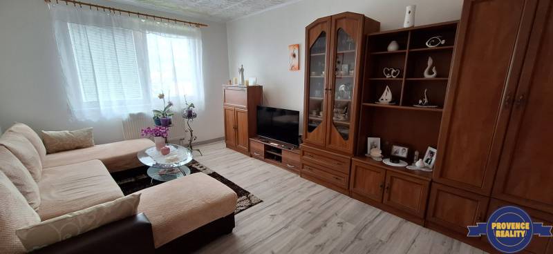 Wohnzimmer in einer 3-Zimmer-Wohnung mit Sofa, Schrank und Fernseher, helle Dekoration.