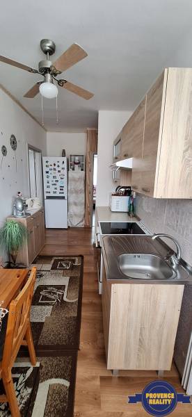 Küche in einer 3-Zimmer-Wohnung mit Holzmöbeln und Deckenventilator.