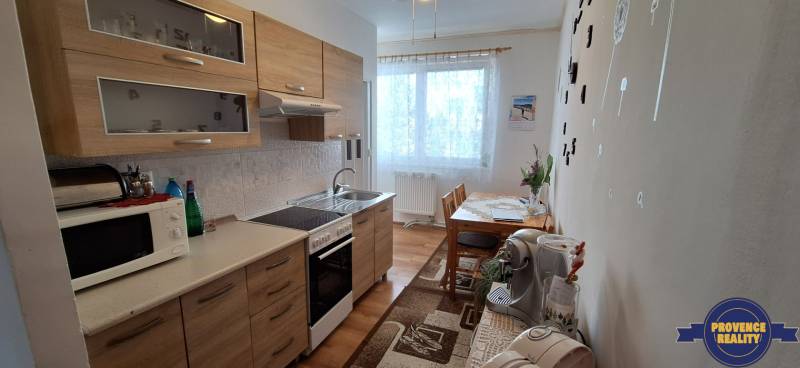 Küche in einer 3-Zimmer-Wohnung mit Holzschränken und Esstisch, helle Dekoration.
