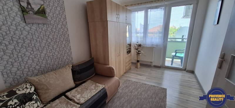 Ein Zimmer in einer 3-Zimmer-Wohnung mit Sofa, Kleiderschrank und Balkon.