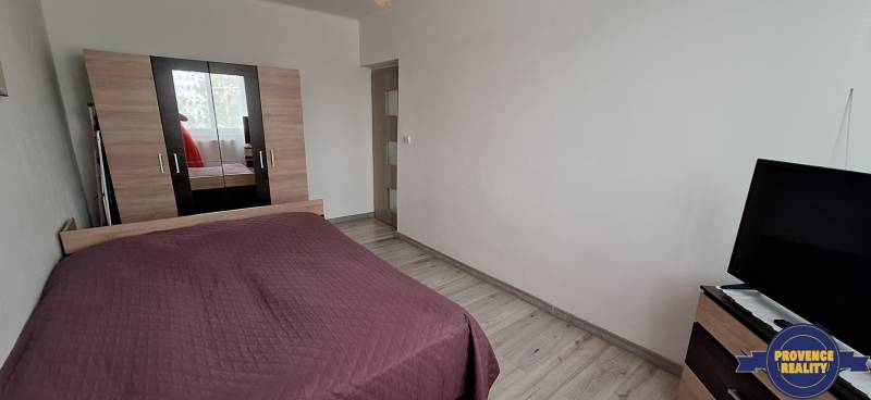 Schlafzimmer mit Bett, weißen Wänden und Schrank, 3-Zimmer-Wohnung.