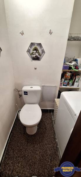 Badezimmer in einer 3-Zimmer-Wohnung mit Toilette, Waschmaschine und Regalen mit Reinigungsmitteln.