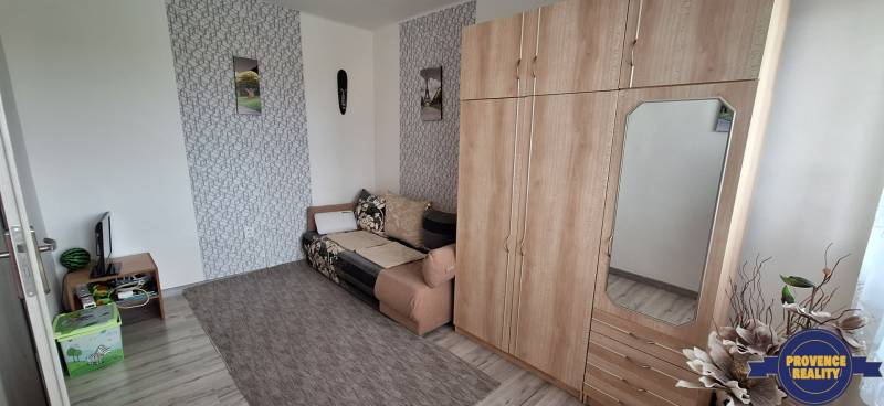 Wohnzimmer in einer 3-Zimmer-Wohnung mit Sofa, Schrank und Wanddekorationen.