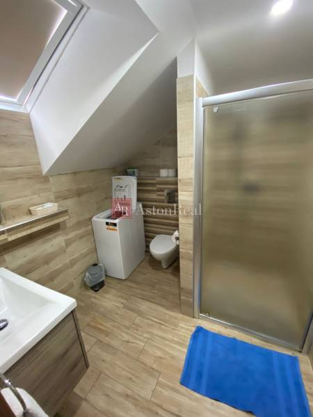 Badezimmer in einem Einfamilienhaus mit Duschkabine, Waschmaschine und Holzverkleidung an den Wänden.
