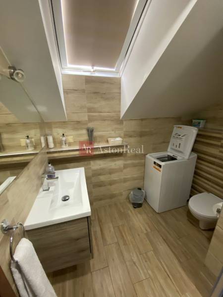 Ein Badezimmer in einem Einfamilienhaus mit Waschbecken, Waschmaschine und Toilette in hellen Holztönen.