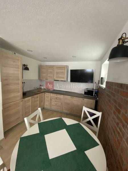 Küche in einem Einfamilienhaus mit Holzmöbeln, Esstisch und Ziegelwand.
