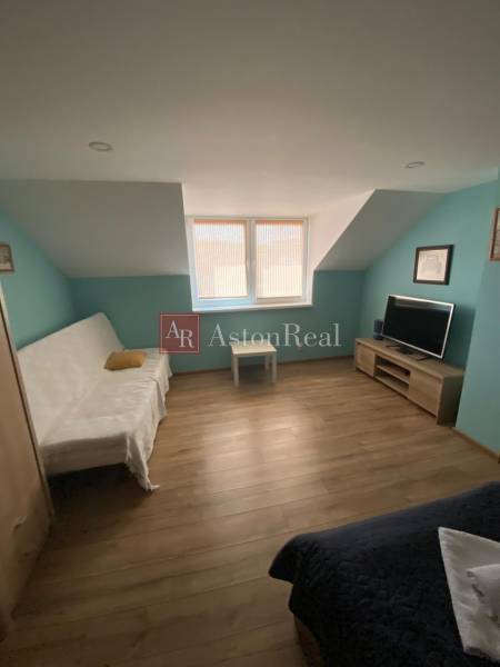 Ein Zimmer in einem Einfamilienhaus mit einem Sofa, einem Fernseher und einem Holzboden.