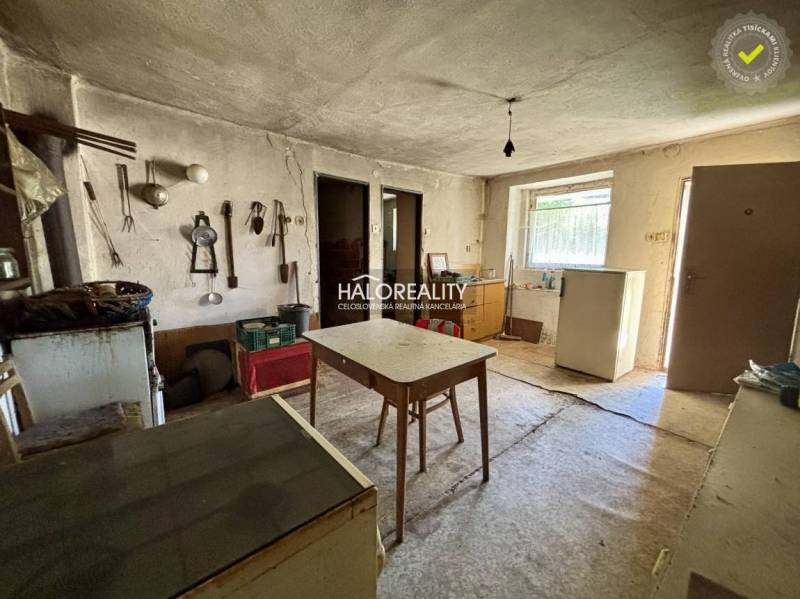 Interieur eines Einfamilienhauses mit Tisch, Kühlschrank und Werkzeugen an der Wand.