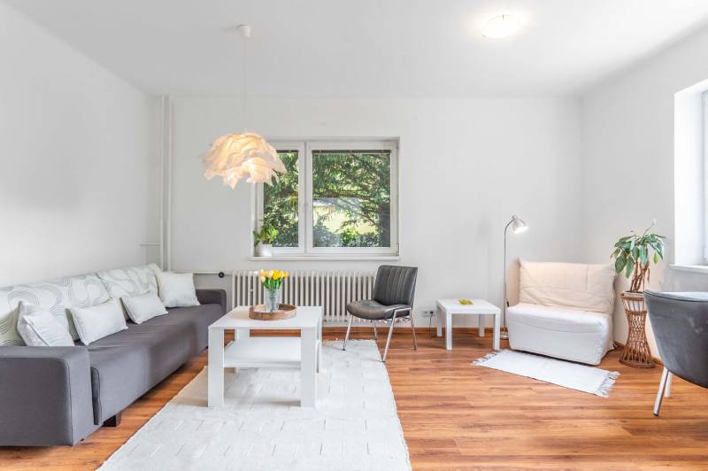 Wohnzimmer einer Zweizimmerwohnung mit Sofa und Holzboden, helle Dekoration.