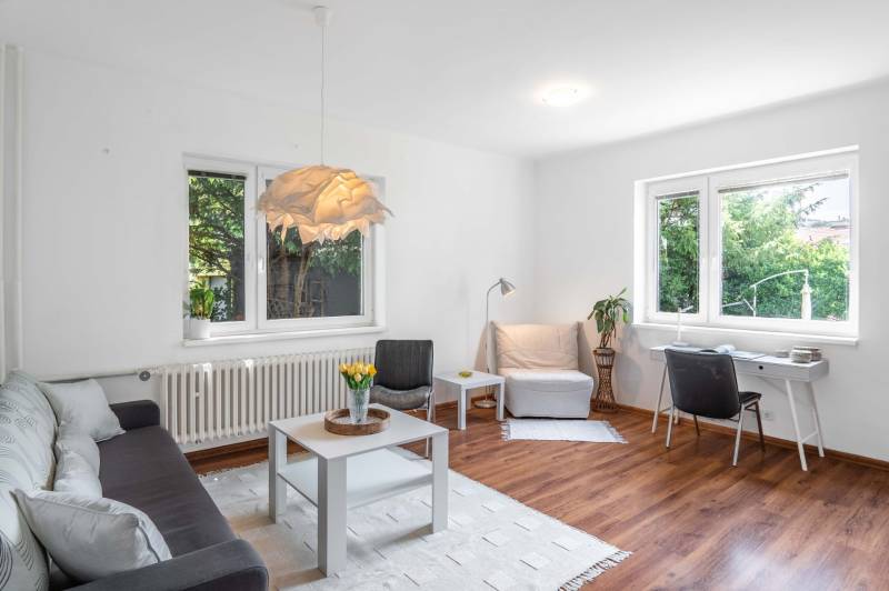 Helles Wohnzimmer in einer 2-Zimmer-Wohnung mit Sofa, Tisch und Schreibtisch.