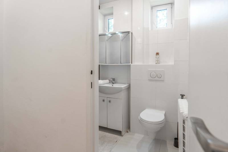 Badezimmer mit Toilette, Waschbecken und Spiegel in einer 2-Zimmer-Wohnung.