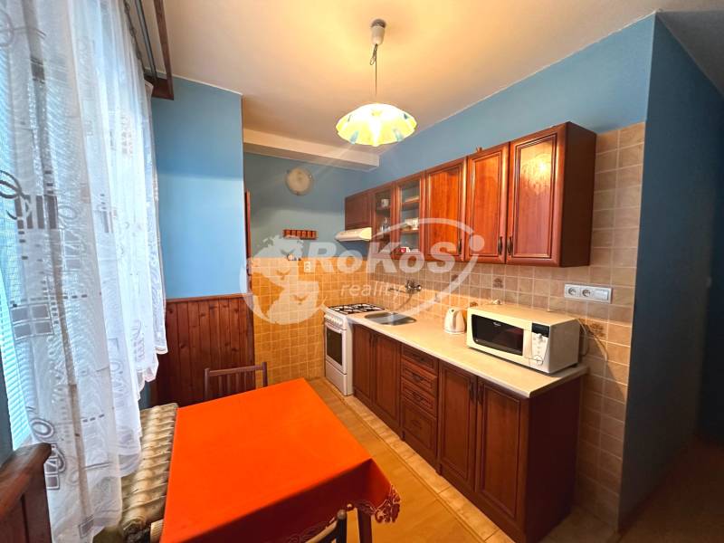 Küche in einer 3-Zimmer-Wohnung mit Holzschränken und Esstisch.
