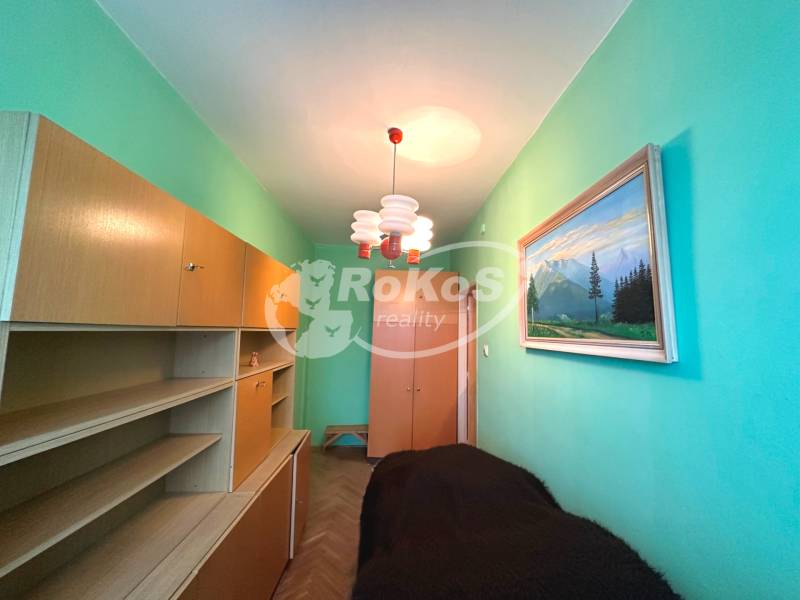 Ein schmales Zimmer in einer 3-Zimmer-Wohnung mit hellen Möbeln und einem Gemälde an der Wand.