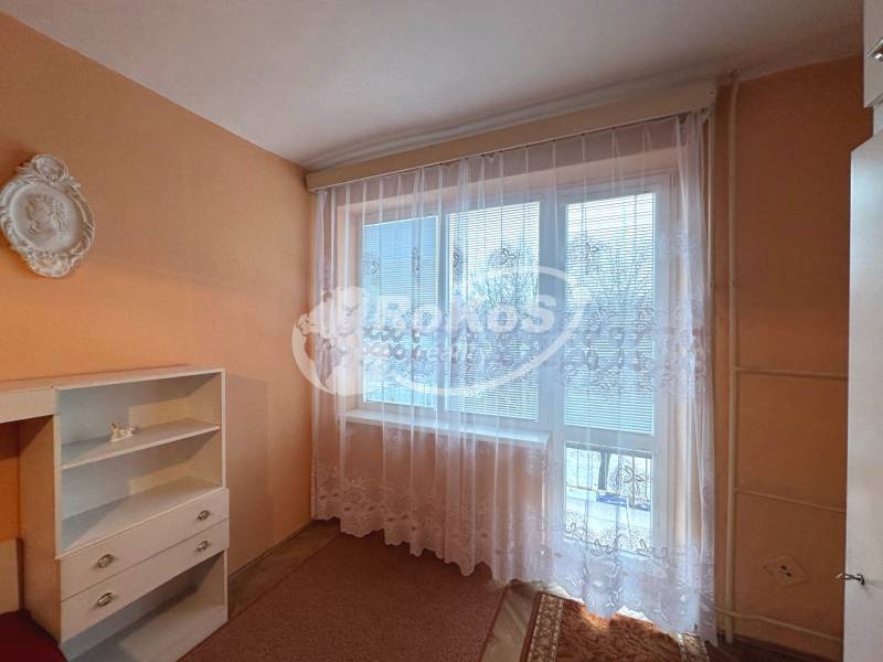 Ein Zimmer in einer 3-Zimmer-Wohnung mit orangefarbenen Wänden und weißen Vorhängen am Fenster.