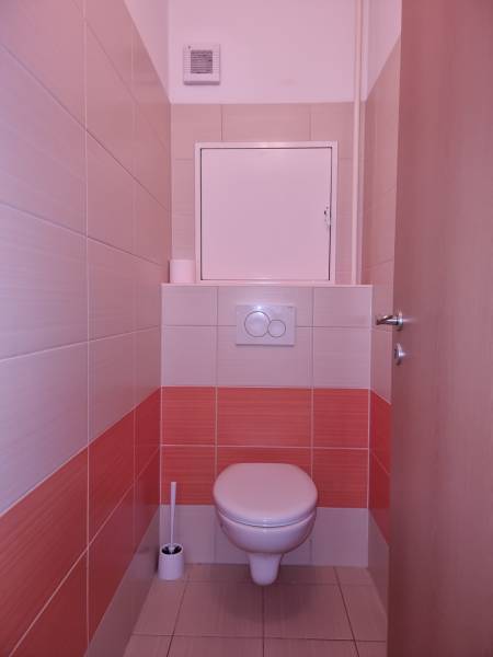 Toilette mit Fliesen in einer orange-weißen Kombination in einer 2-Zimmer-Wohnung.