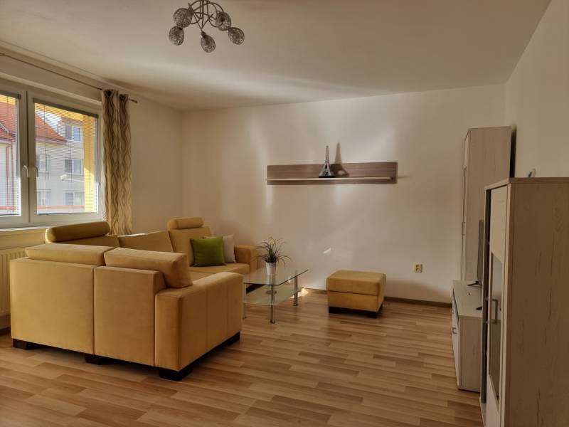 Wohnzimmer in einer 2-Zimmer-Wohnung mit gelbem Sofa und Holzboden.