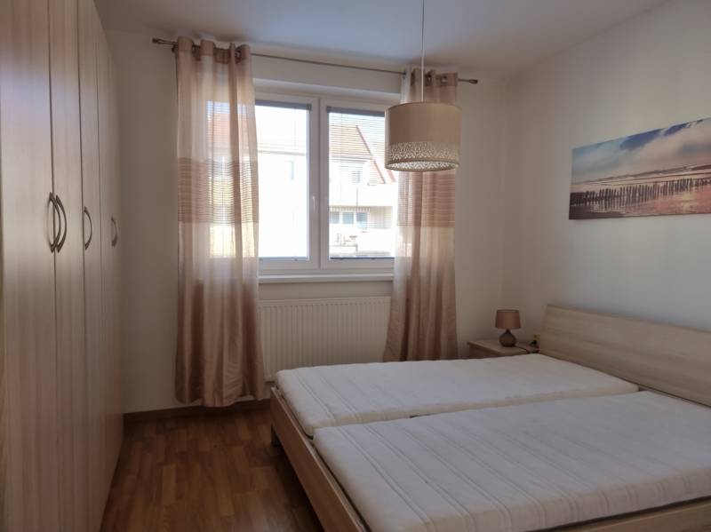 Schlafzimmer mit zwei Betten, Einbauschrank und Bild in einer Zweizimmerwohnung.