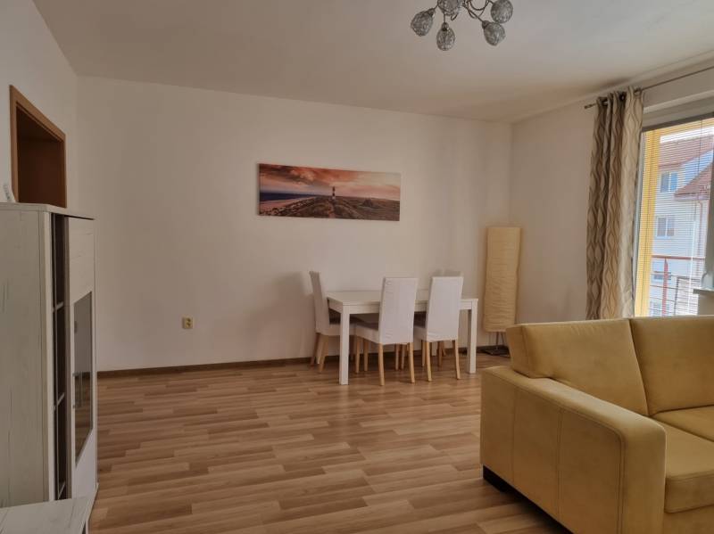 Wohnzimmer mit Esstisch und gelbem Sofa in einer Zweizimmerwohnung.