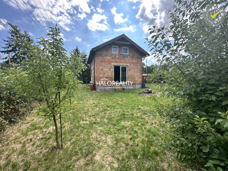 Eine Hütte in Vinosady mit einem großen Garten und einem Holzbau unter blauem Himmel.