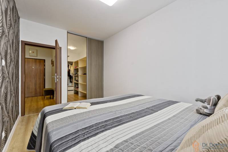Schlafzimmer mit Bett, Buch, Plüschtier und Einbauschrank in einer 2-Zimmer-Wohnung.