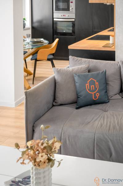 Wohnzimmer mit Küche in einer 2-Zimmer-Wohnung, Kombination aus Holz- und schwarzen Elementen.