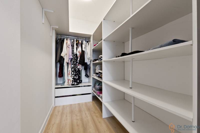 Ein Kleiderschrank in einer 2-Zimmer-Wohnung mit Regalen und einem Hängeplatz für Kleidung.