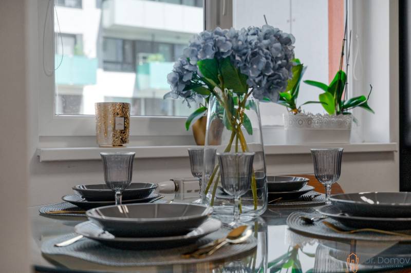 Ein elegant gedeckter Tisch mit Blumen in einer 2-Zimmer-Wohnung, Glasgeschirr und Besteck.