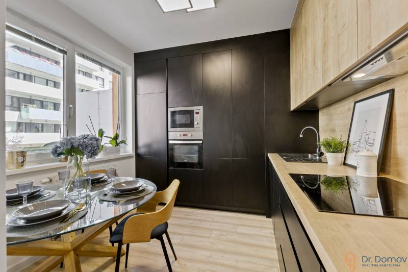 Küche in einer 2-Zimmer-Wohnung mit Esstisch und moderner schwarzer Küchenzeile.