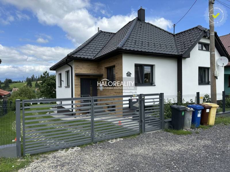 Ein Einfamilienhaus in Liptovský Hrádok mit modernem Schrägdach und Tor, daneben stehen Mülltonnen.