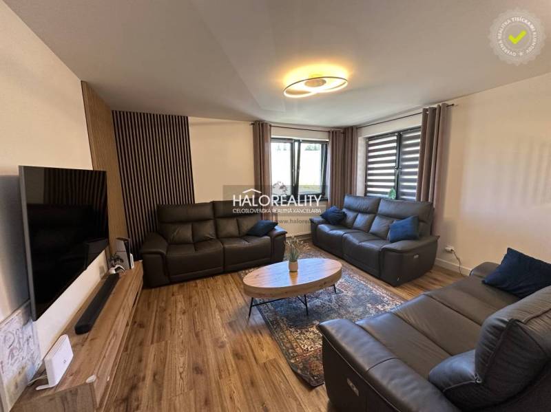 Wohnzimmer in einem Einfamilienhaus mit Ledersofas, Holzboden und moderner Beleuchtung.