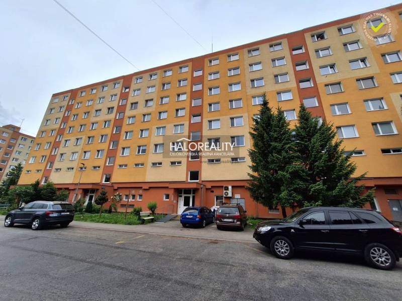 Wohnhaus in Prievidza mit Parkplätzen und Grünflächen, geeignet für eine 3-Zimmer-Wohnung.