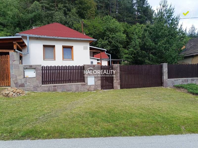 Ein Ferienhaus in Helcmanovce mit einem Holzzaun und gepflegtem Rasen, umgeben von Grün.