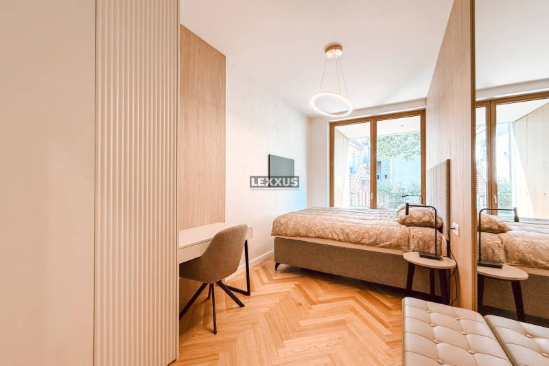 Schlafzimmer mit Tisch und Stuhl in einer 4-Zimmer-Wohnung, mit großem Fenster und Holzboden.