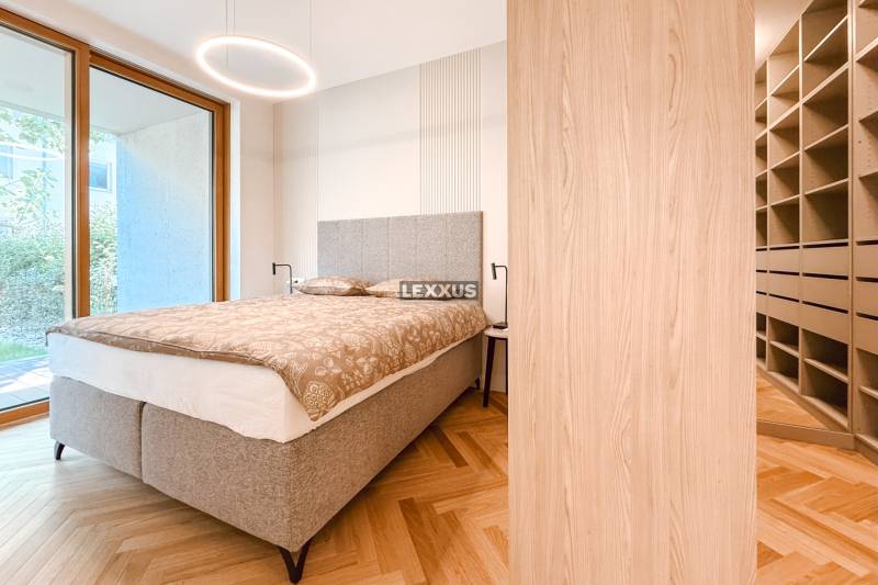 Schlafzimmer mit grauem Bett, Einbauschrank, Parkettboden und Ausblick in einer 4-Zimmer-Wohnung.