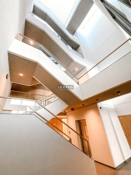 Eine breite Treppe mit beleuchtetem Deckenfenster in einer 4-Zimmer-Wohnung, mit Holz- und Glaselementen.
