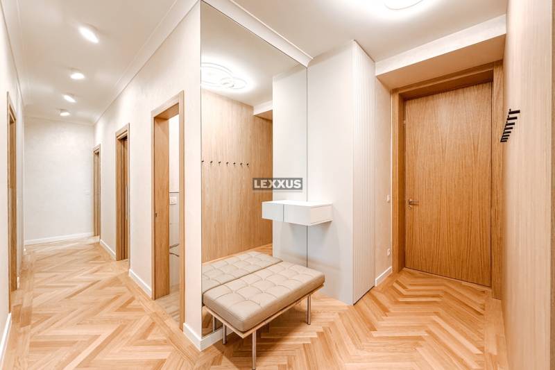 Geräumiger Flur mit Spiegel und Bank in einer 4-Zimmer-Wohnung mit Holztüren.