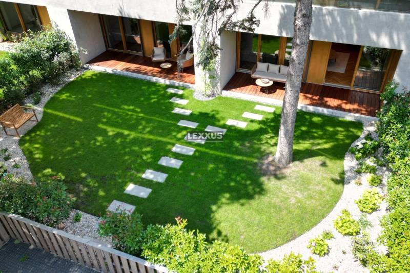 Gartenterrasse einer 4-Zimmer-Wohnung mit Rasen und Holzmöbeln.