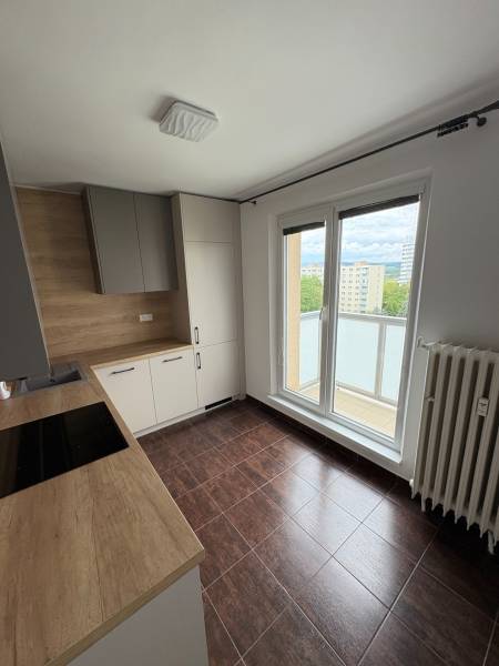 Küche in einer 2-Zimmer-Wohnung mit einer Holzarbeitsplatte und Zugang zum Balkon.