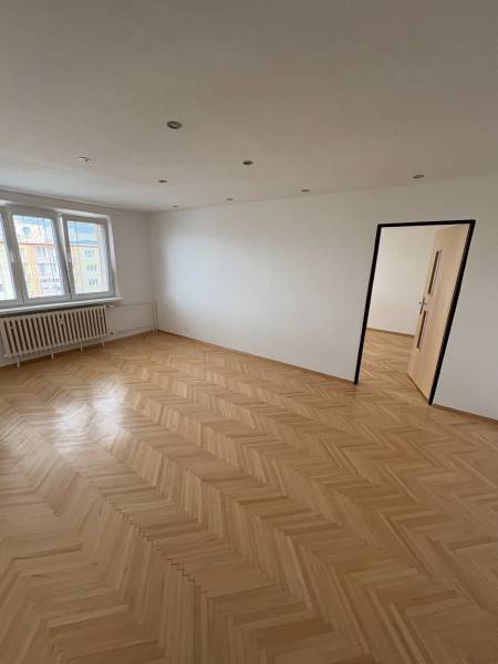 Ein Zimmer mit Parkettboden, weißen Wänden und Fenstern, Teil einer 2-Zimmer-Wohnung.