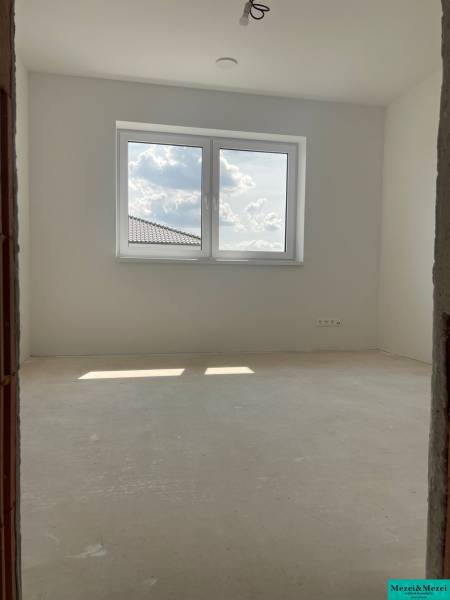 Ein Zimmer mit weißen Wänden und einem großen Fenster in einem Einfamilienhaus.