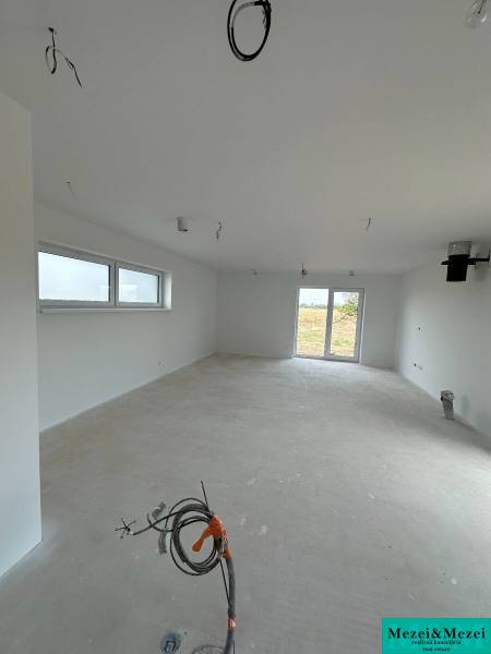 Ein unmöblierter Raum mit Fenstern, Türen und Vorbereitung für die Elektroinstallation in einem Einfamilienhaus.
