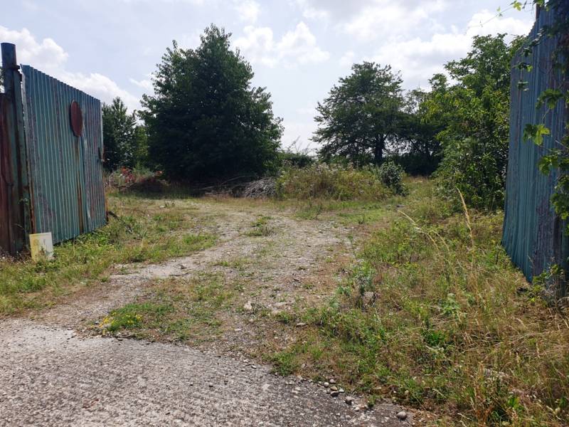 Eingezäunter Zugang zu Gewerbegrundstücken in Trenčianske Bohuslavice mit Grünflächen und Gehweg.